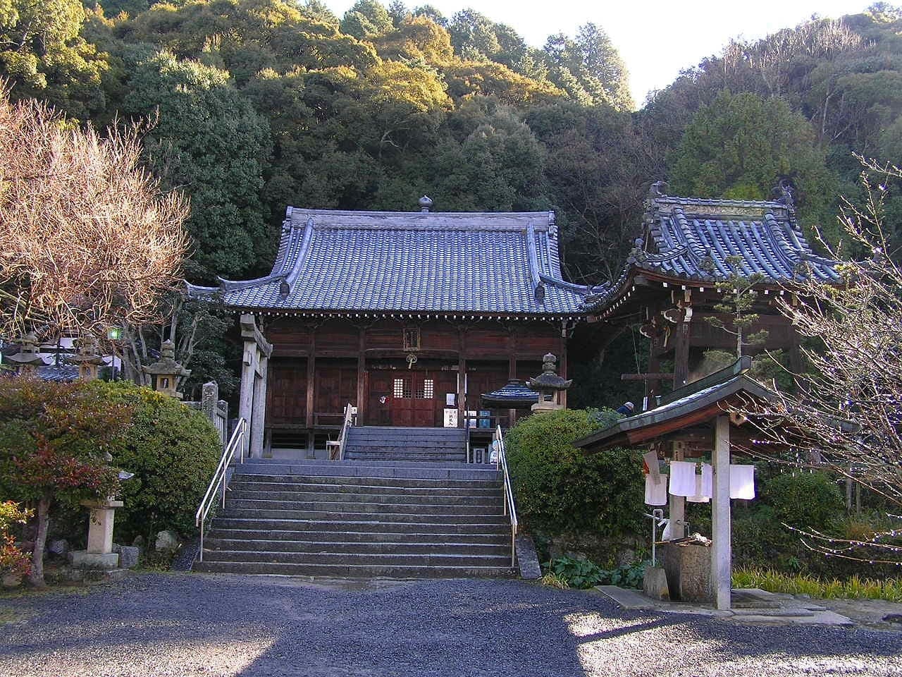 Esterno del tempio Hanta-ji con scale in pietra, sala in legno, tetti di tegole e alberi tutt'intorno.