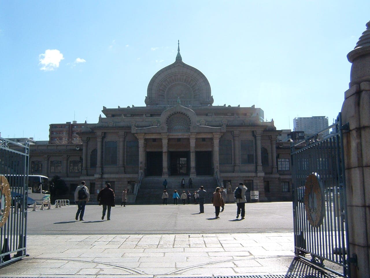 Tsukiji Hongan-ji temple exterior with a large central dome, open gates, and a few people in the courtyard under a clear sky.
