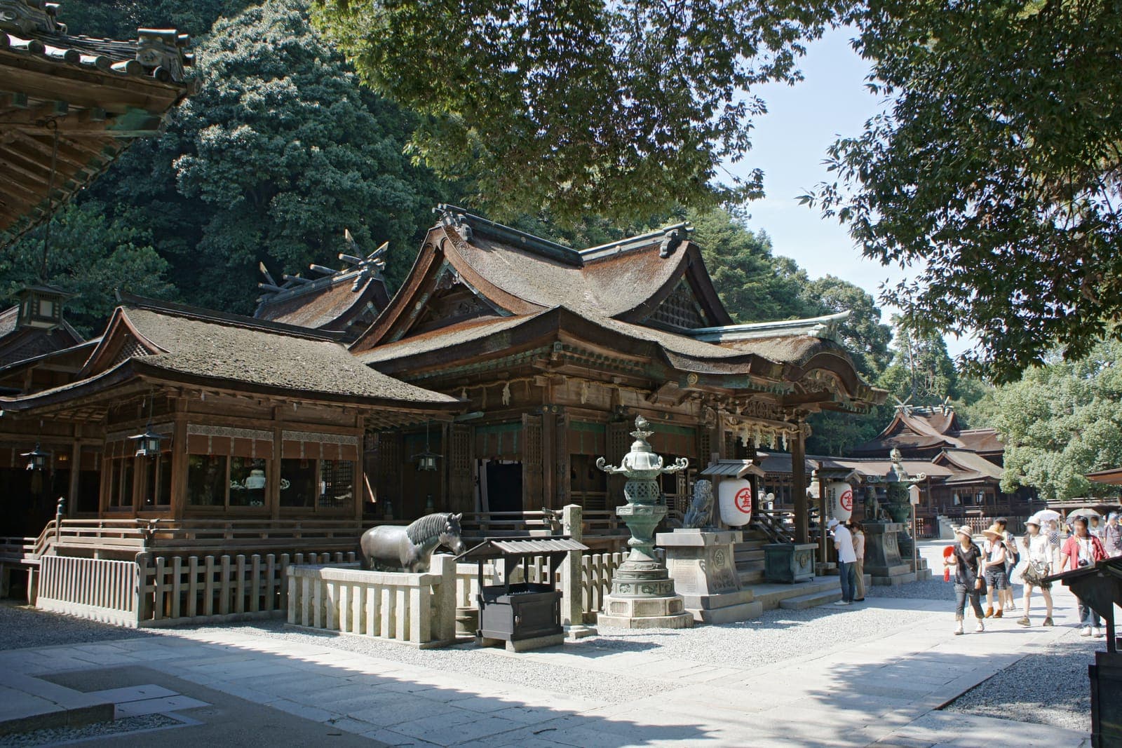 Exterior of Kotohira-gu, with wooden shrine buildings, stone lanterns, and visitors on a gravel path.
