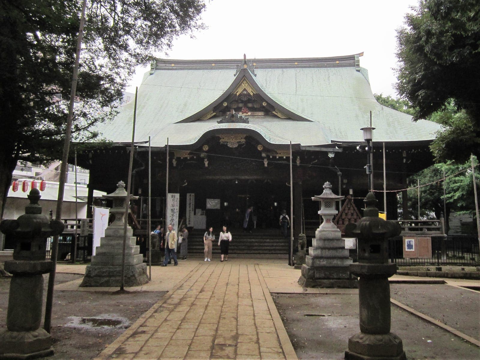 Zoshigaya Kishimojin-do with its broad copper roof, carved entrance, stone lanterns and paved approach.