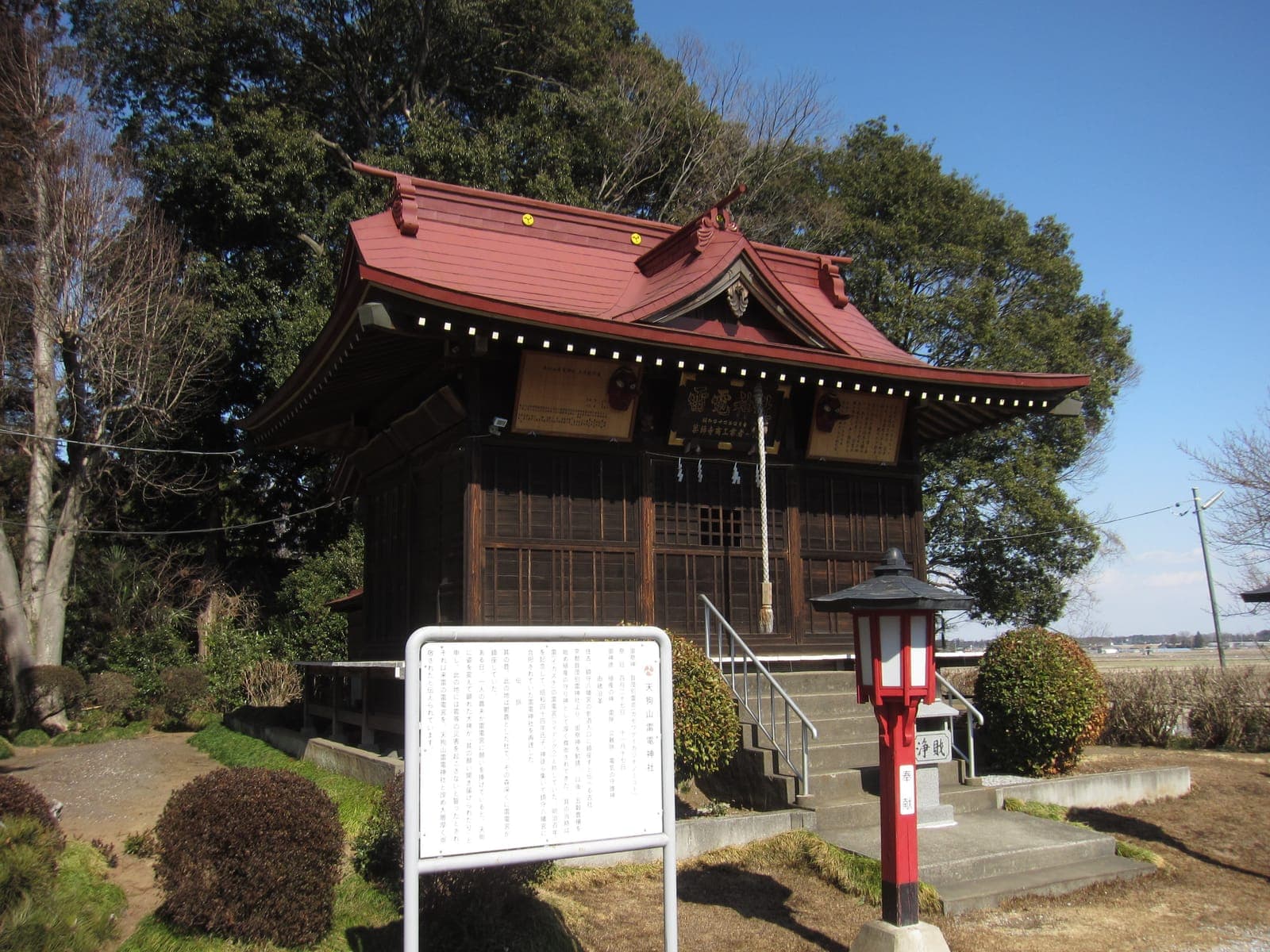 Exterior of Otaru Tenguyama Jinja, a small wooden shrine with a red roof, steps, a lantern, and a signboard.