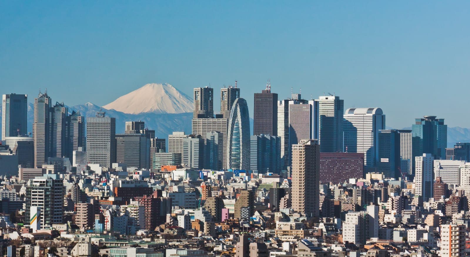 Tokyo skyline with Mount Fuji in the background under a clear blue sky.
