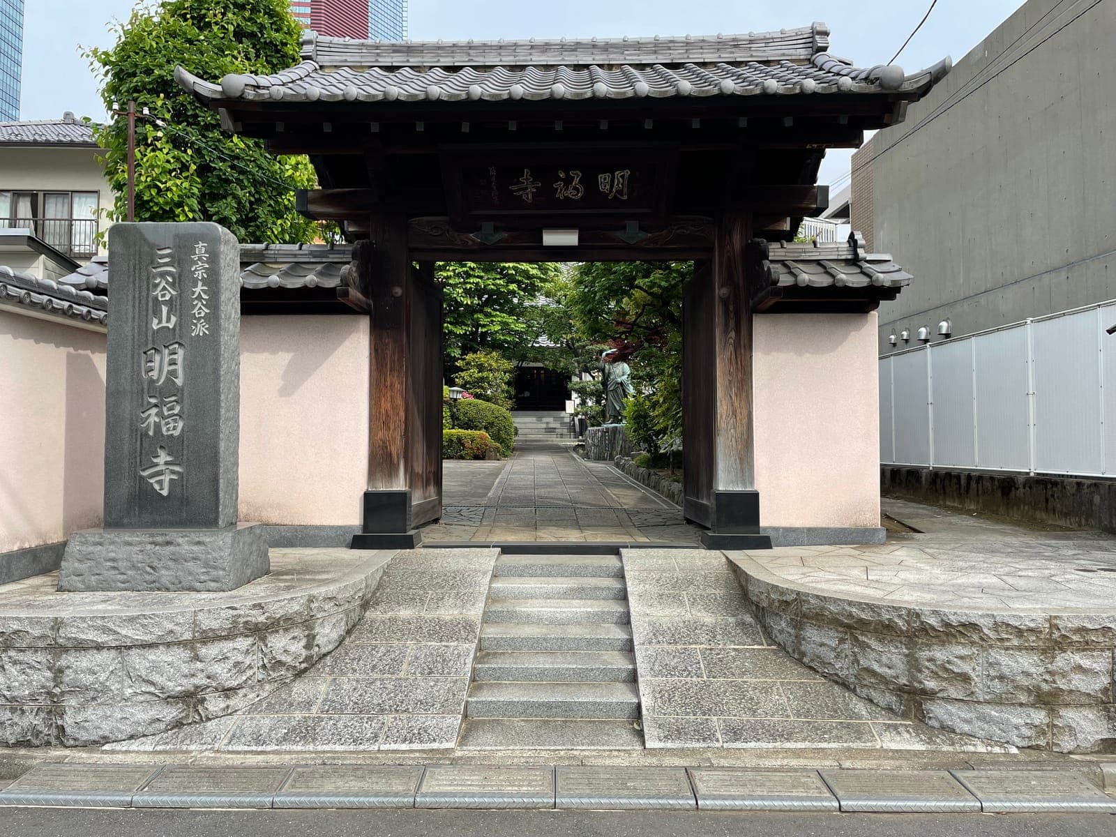 Puerta de entrada del templo Myofuku-ji con una estela de piedra, techo de tejas y un camino hacia un pequeño jardín.